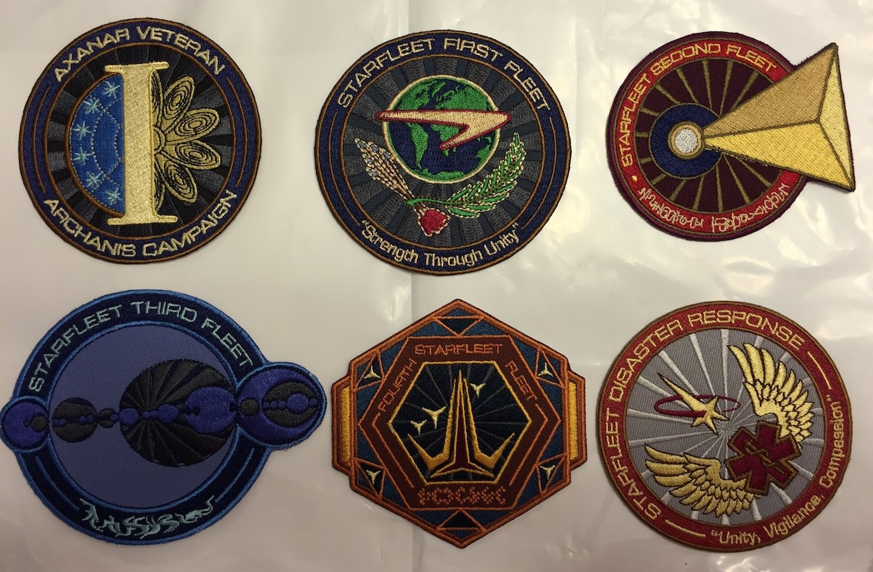 Six embroidered patches in the style of authentic Star Trek Starfleet Command uniform patches, bearing text like 'Anaxar Veteran: Archanis Campaign' and 'Starfleet Disaster Response: Unity, Vigilance, Compassion' around the outside.
