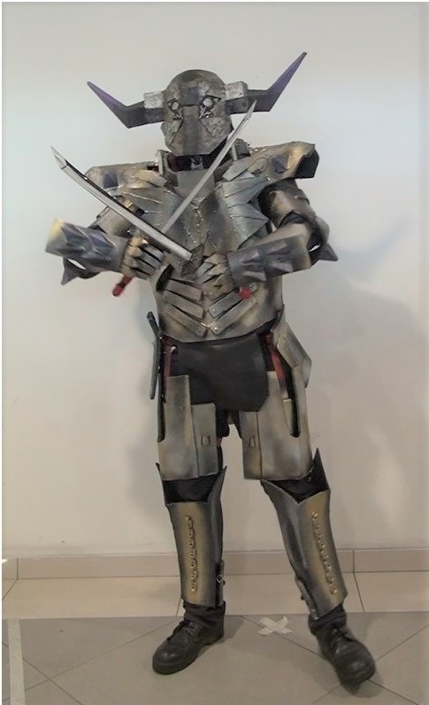 Cosplayer wearing whole body armor, posing with two swords crossed on his chest