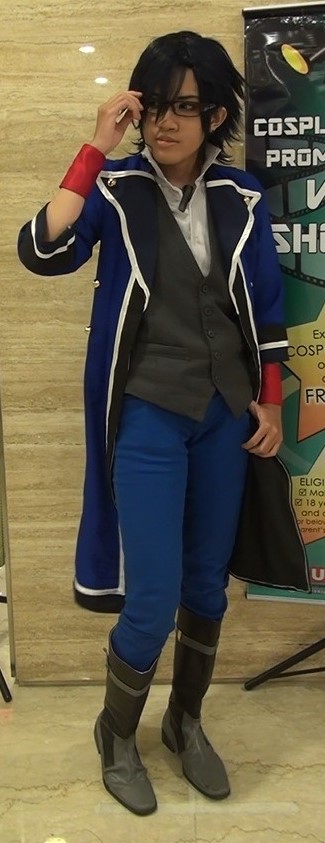 Cosplayer wearing a tailcoat jacket and red wrist bands, touching his black-framed glasses