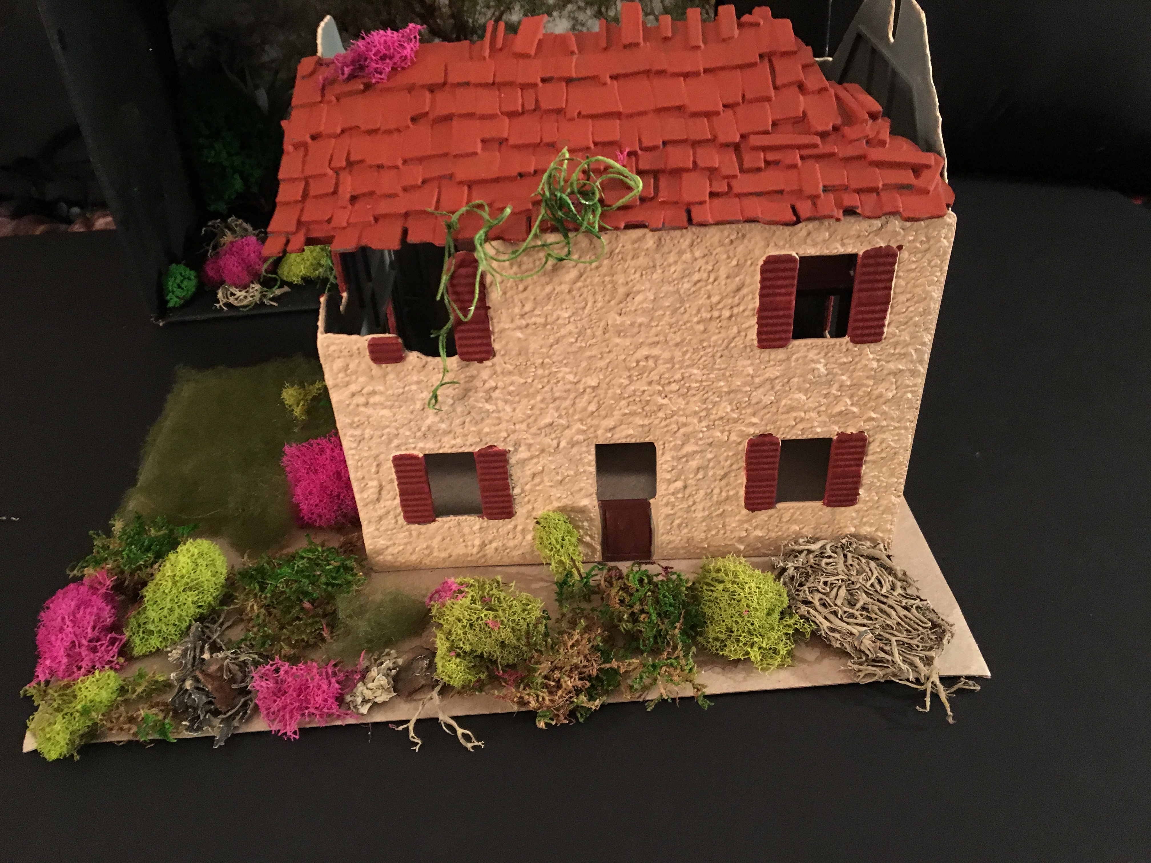 Tabletop model of a dilapidated stucco two-story house