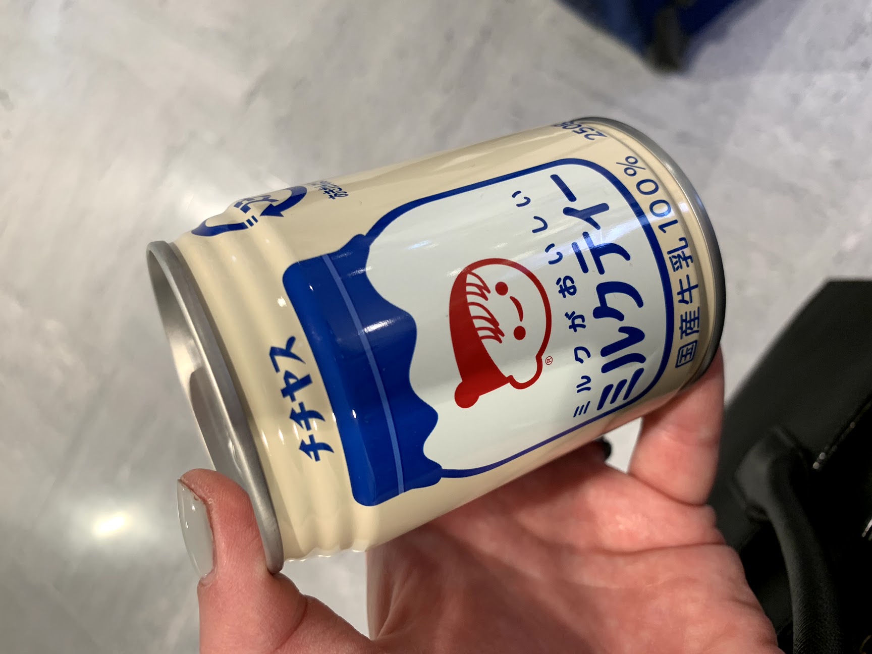 Hand holding a can of hot tea with Japanese writing