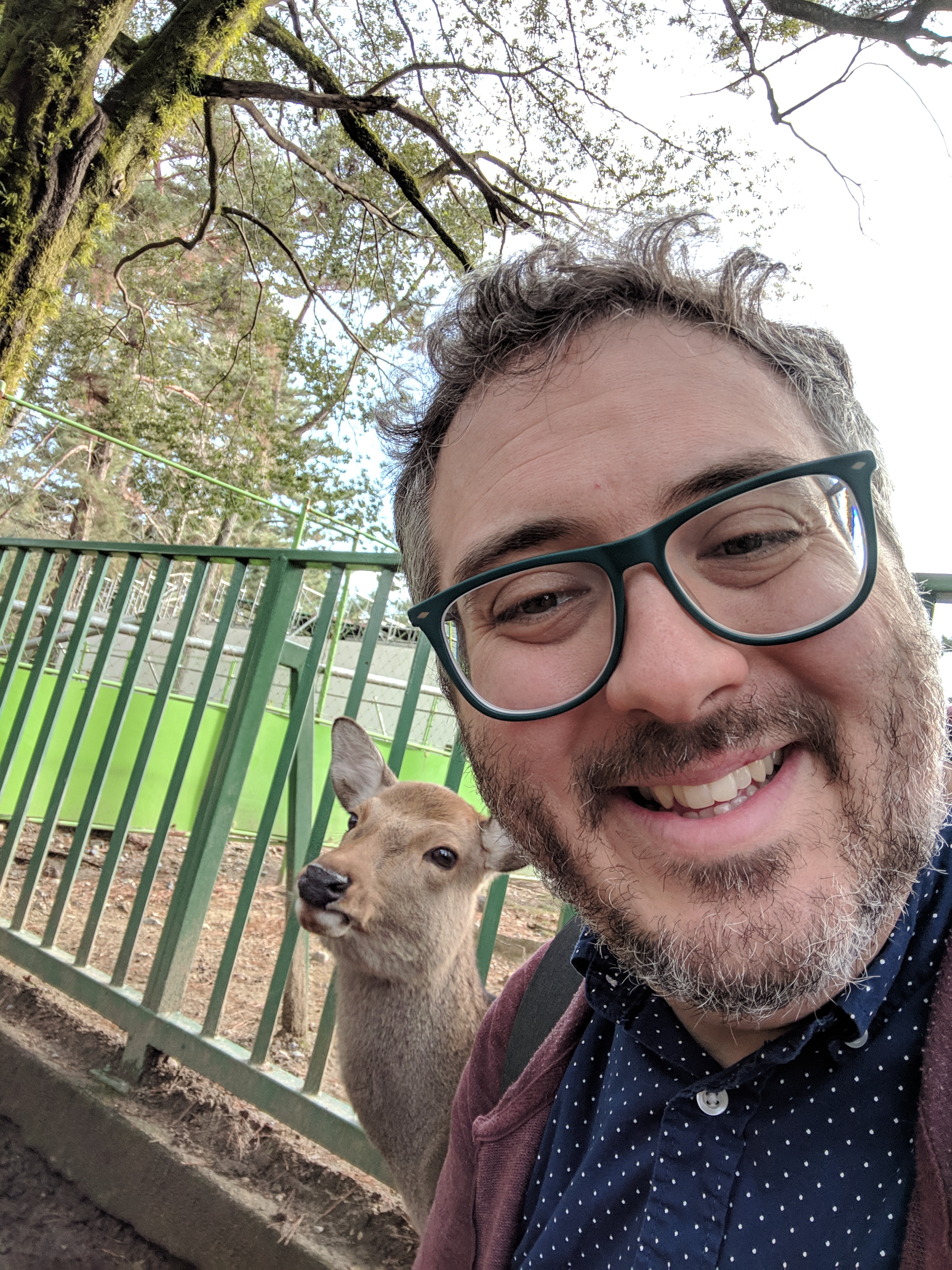Man smiling with a deer close behind him