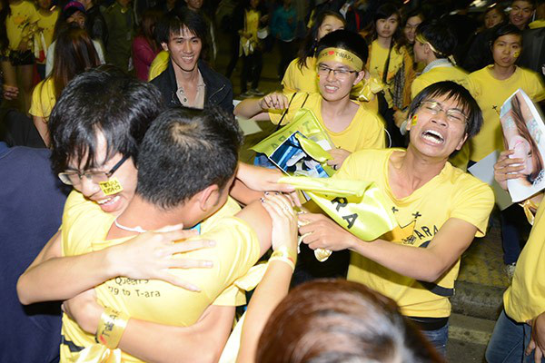 A crowd of fans in matching yellow t-shirts overcome with emotion. Le, who is crying out, is particularly noticeable.