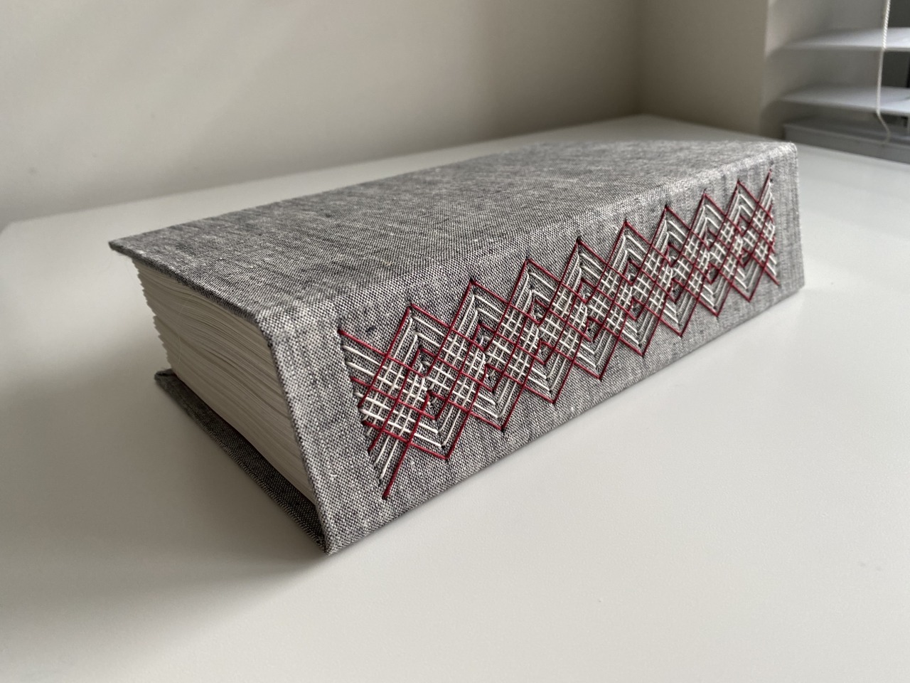 Side-lying hardcover book with ornate red-and-white stitching ...
