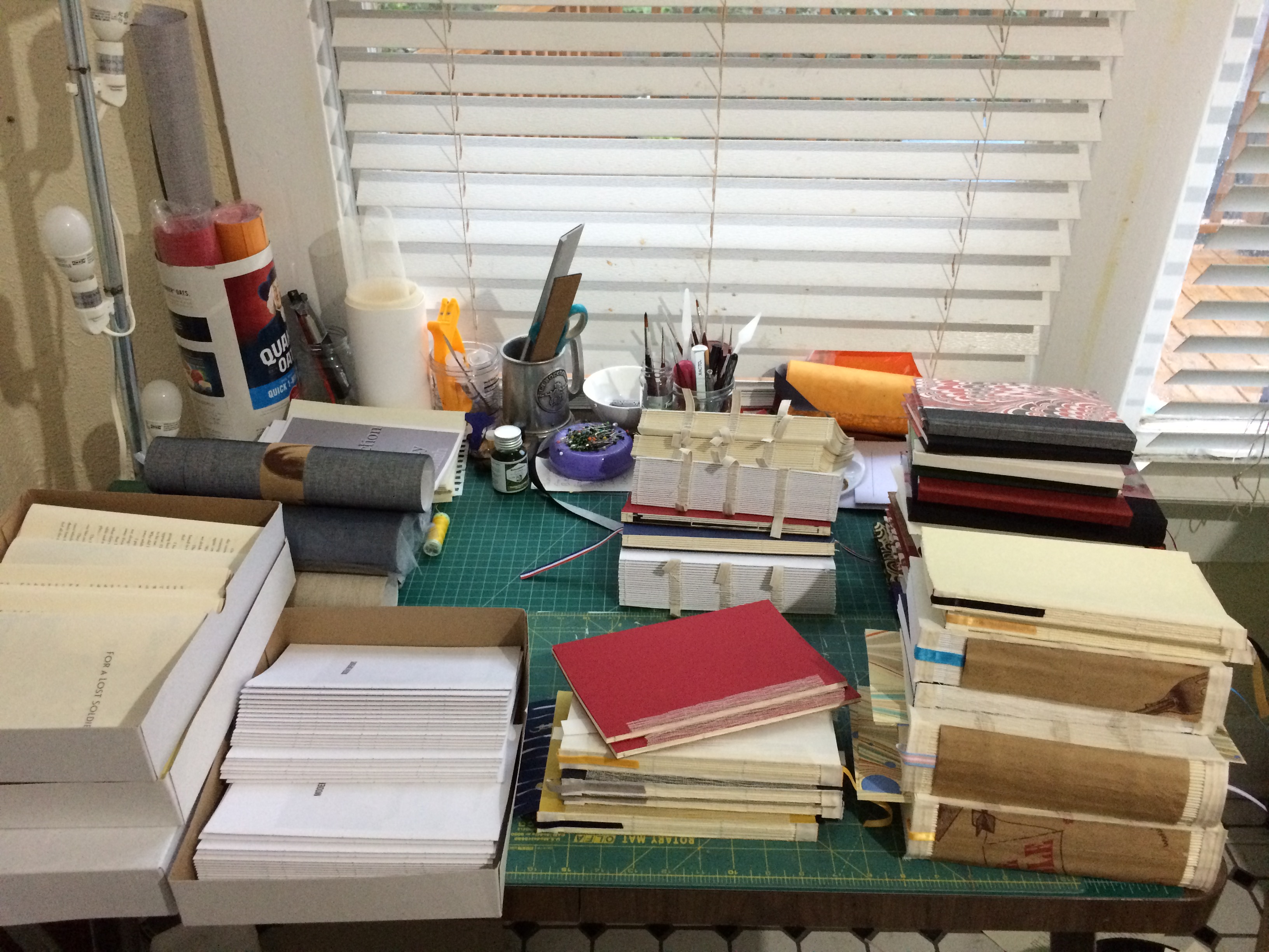 Desktop with neat piles of folded signatures in various book production stages