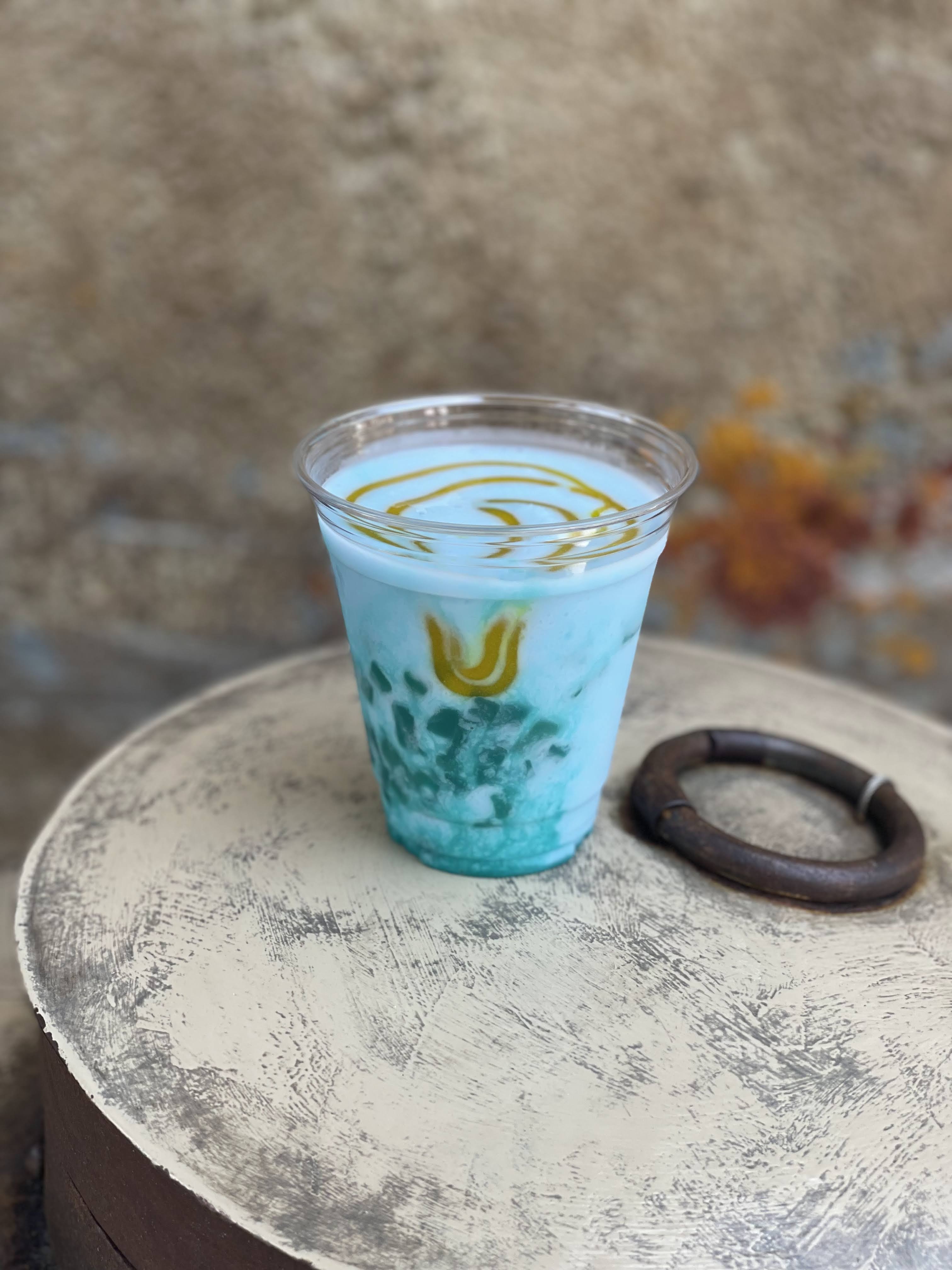 A plastic cup filled with blue milk and glittery gel.