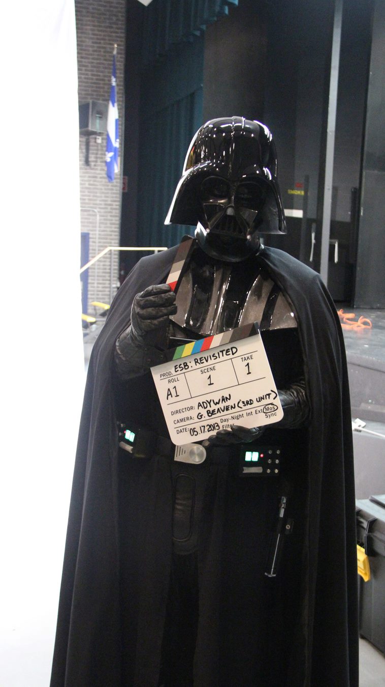 Color photo of person dressed as Darth Vader holding a film slate.