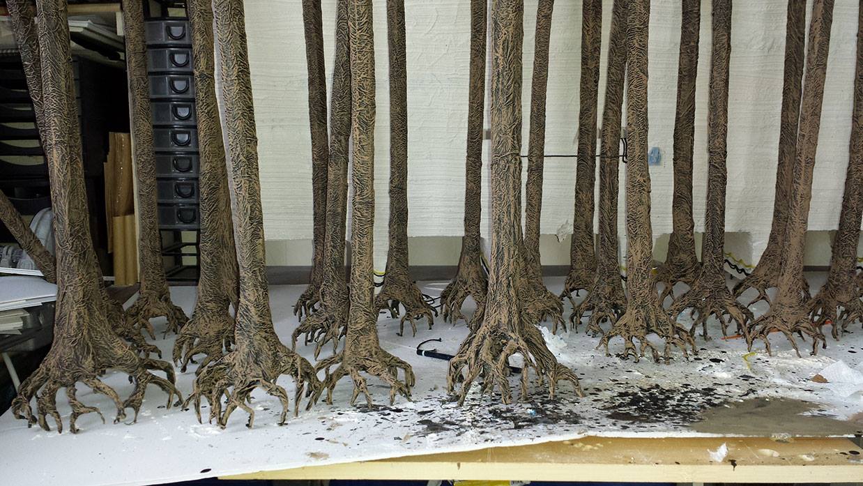 Color image of trees, including roots, standing in a workshop.